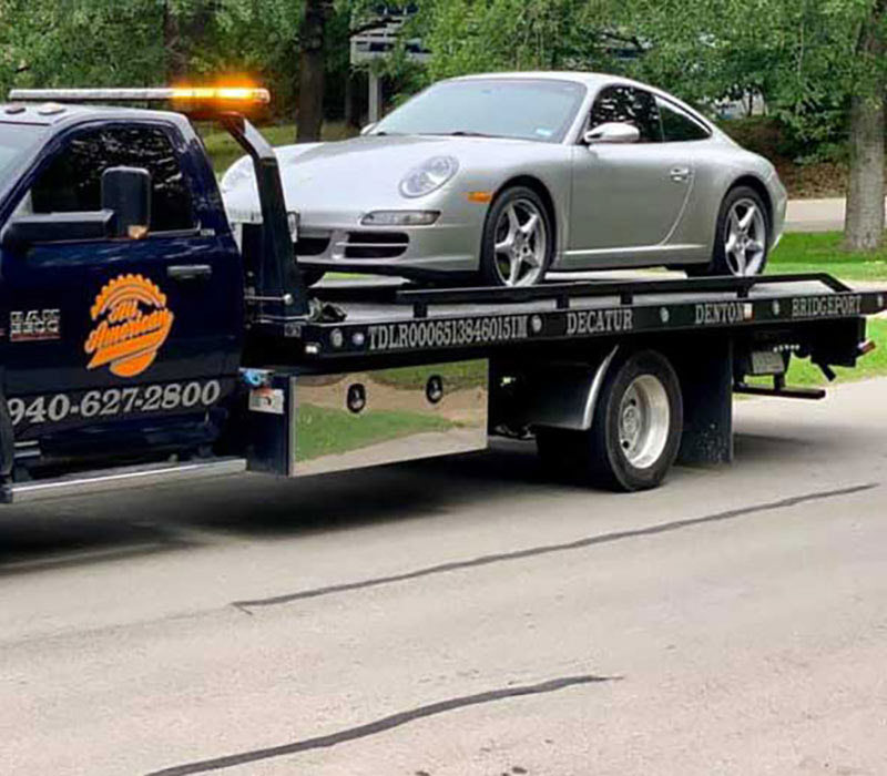 All American Towing flatbed towing a Porsche in Denton County