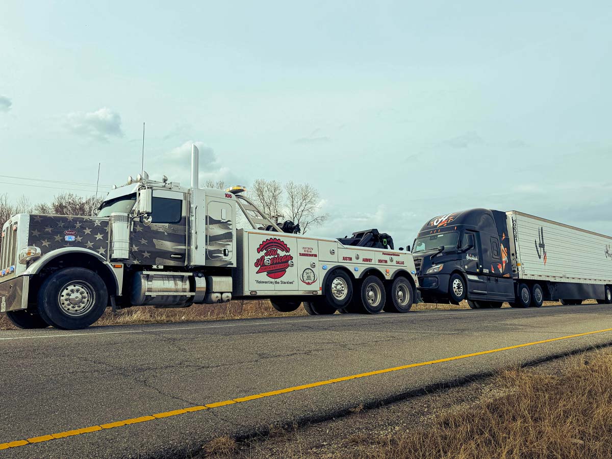 All American Towing heavy duty wrecker towing a tractor trailer on the highway in San Antonio